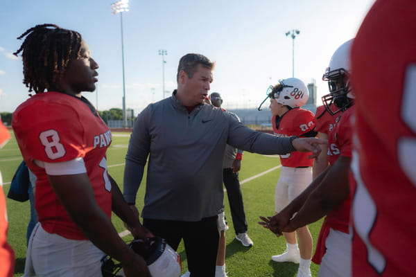 A football coach talking and gesturing to players on the field