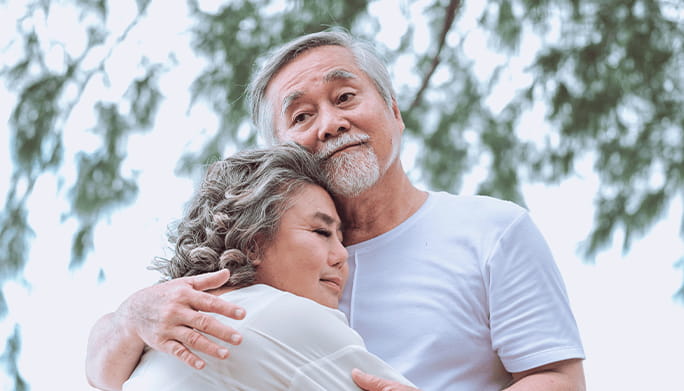 Couple hugging outside with concerned look on their faces.